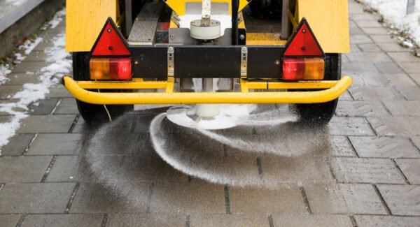 A machine is sprinkling salt on a sidewalk
